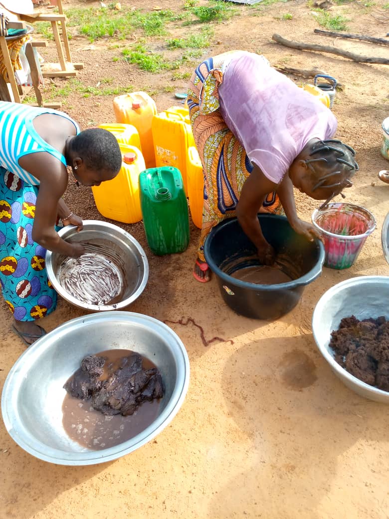 2 women bending over to do shea butter transformation