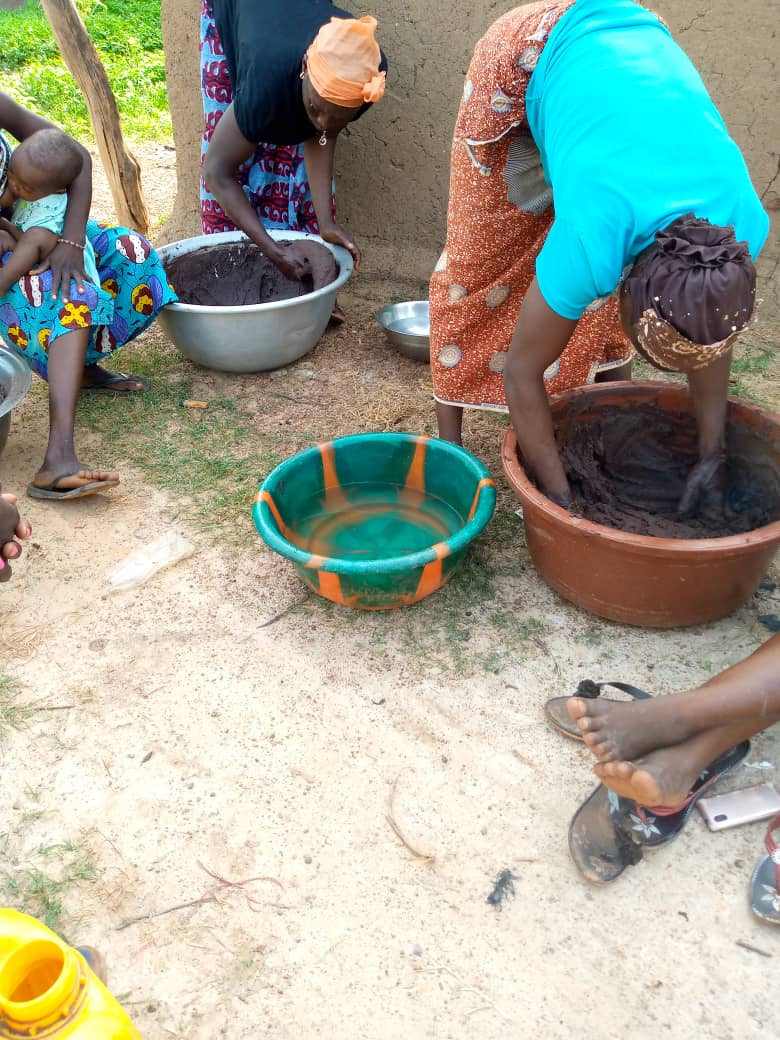 2 women bending over to do shea butter transformation